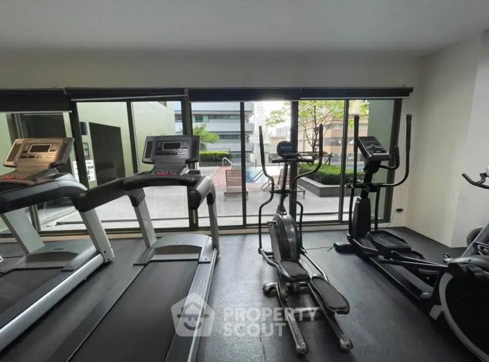 Modern gym with state-of-the-art equipment and large windows offering a city view.