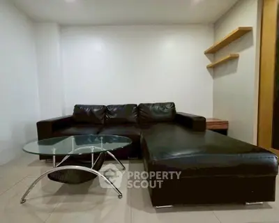Modern living room with sleek black leather sofa and glass coffee table