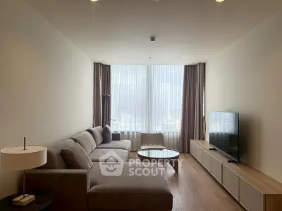 Spacious modern living room with large sofa and flat-screen TV, featuring floor-to-ceiling windows.
