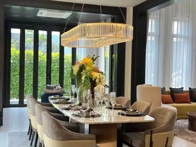 Luxurious dining room with elegant chandelier and large windows offering garden views, perfect for entertaining.