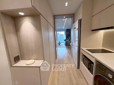 Modern kitchen with sleek appliances and open layout leading to a bright living area with city view.