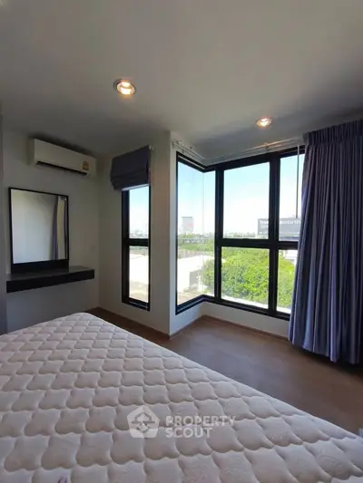 Bright bedroom with large windows and scenic view, featuring modern decor and ample natural light.