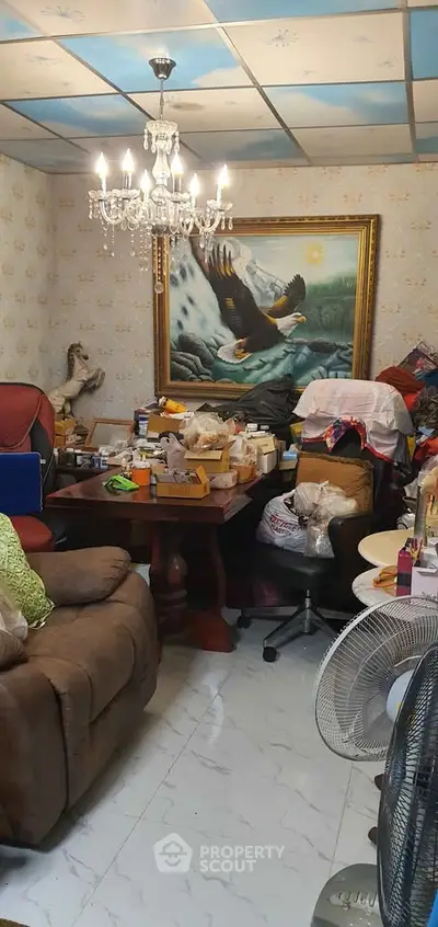 Cozy living room with chandelier and eclectic decor, featuring a large eagle painting and comfortable seating.