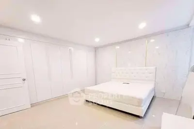 Spacious modern bedroom with white decor and ample closet space