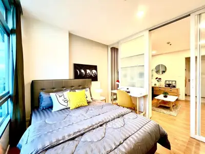 Modern bedroom with stylish decor and adjoining study area in a bright apartment.