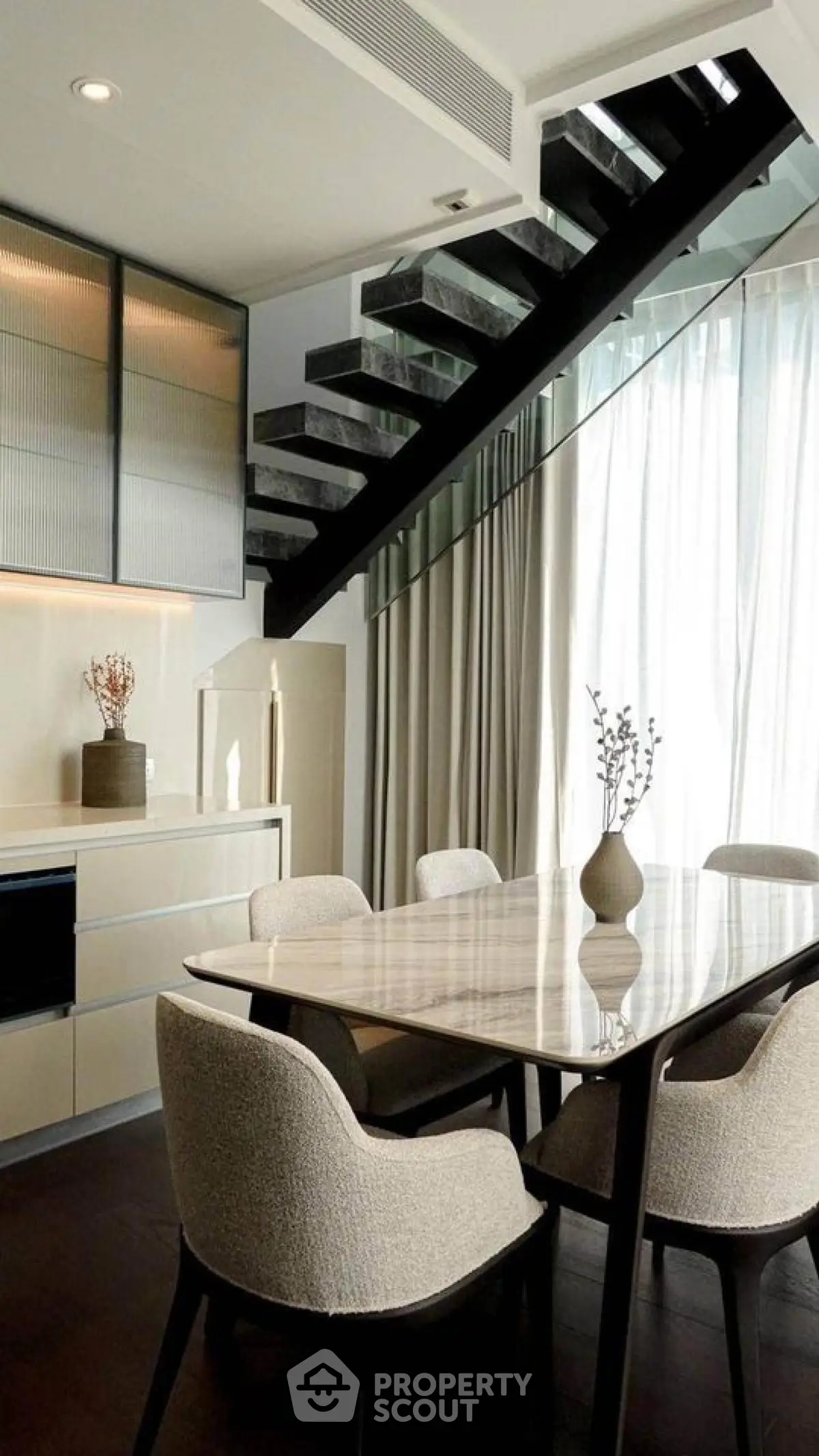 Elegant dining area with modern staircase and natural light