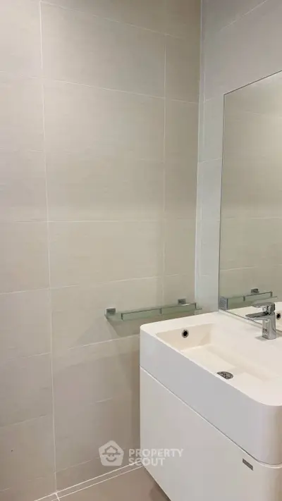 Modern bathroom with sleek sink and large mirror in a minimalist design.