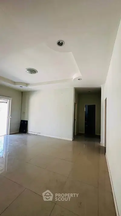 Spacious empty room with modern ceiling design and tiled flooring, ready for customization.