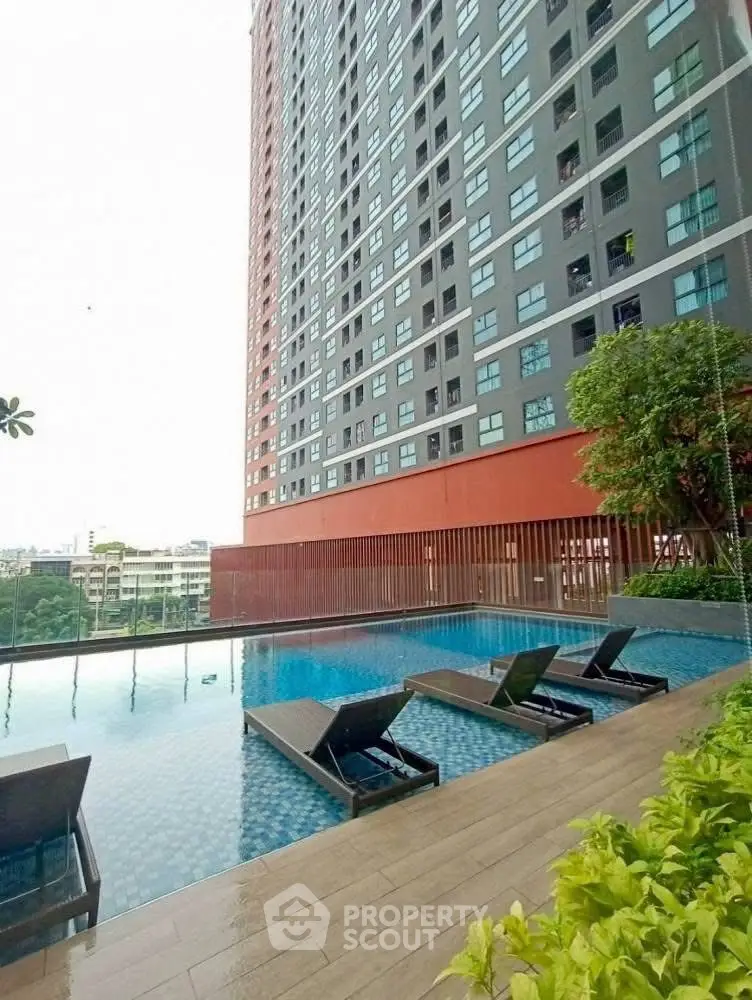 Modern high-rise building with luxurious poolside area and sun loungers.