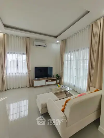 Elegant living room with modern decor, large windows, and cozy seating area.