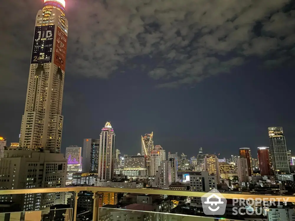 Stunning city skyline view from a high-rise balcony at night, showcasing vibrant urban lights.