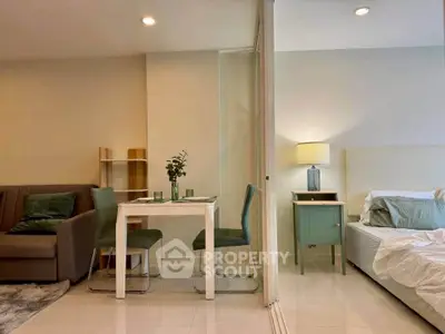 Modern studio apartment with cozy living area and stylish bedroom separated by glass partition.