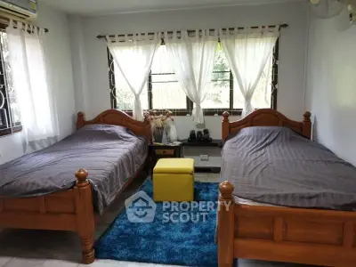 Cozy bedroom with twin beds, wooden furniture, and bright natural light.