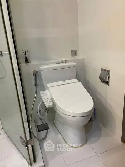 Modern bathroom with sleek toilet and glass shower enclosure in contemporary apartment.