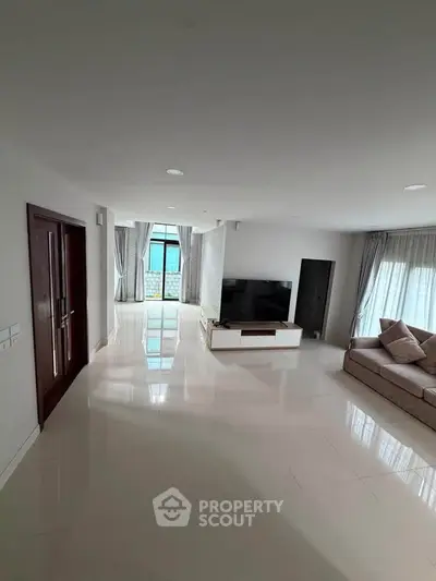 Spacious modern living room with large windows and sleek furnishings in a luxury apartment.
