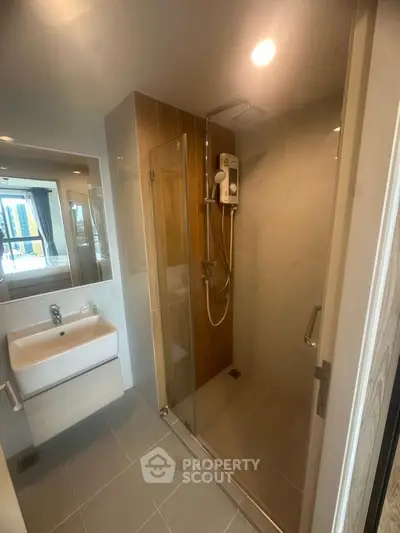 Modern bathroom with glass shower and sleek vanity in contemporary apartment.