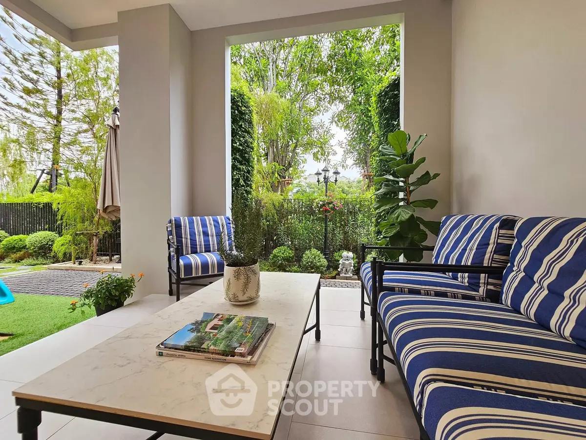 Charming garden view from a stylish patio with striped furniture and lush greenery.