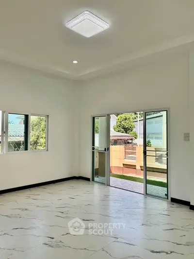 Spacious modern living room with marble flooring and large windows for natural light.