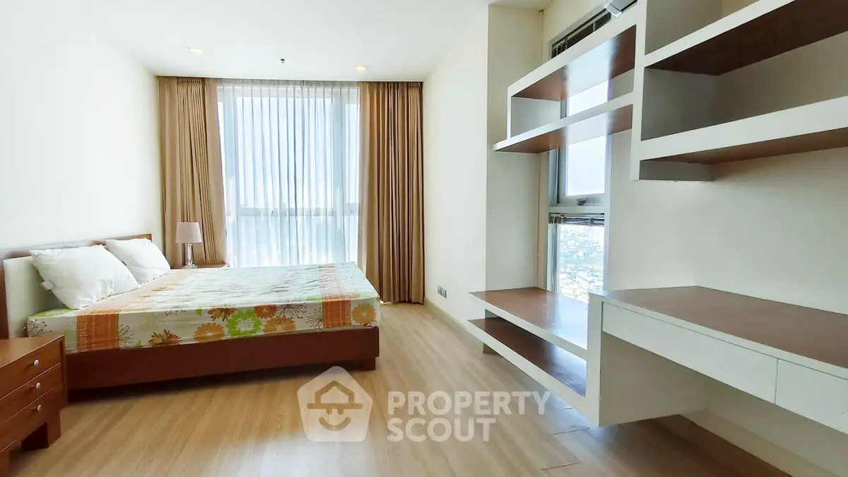 Spacious bedroom with modern design and large window offering natural light and city view.