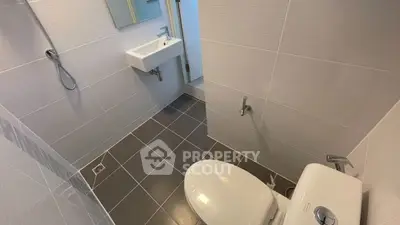 Modern bathroom with sleek fixtures and tiled walls, featuring a compact design and efficient layout.