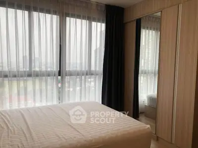 Modern bedroom with large windows and city view, featuring sleek wooden wardrobe and cozy bed.