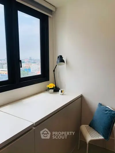 Cozy study nook with city view, featuring a desk, lamp, and chair.