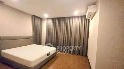 Spacious bedroom with modern design and air conditioning, featuring elegant curtains and wooden flooring.