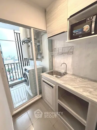 Modern kitchen with balcony view, featuring sleek cabinetry and integrated appliances.