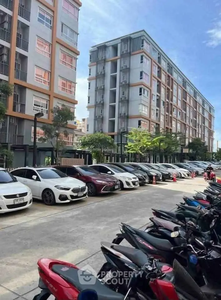 Modern apartment complex with ample parking and vibrant urban setting.