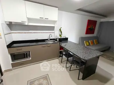Modern kitchen with sleek cabinetry and granite countertop in open layout apartment.