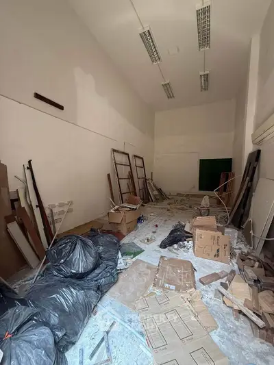Spacious unfinished room with high ceilings, ideal for renovation or storage, featuring scattered construction materials.