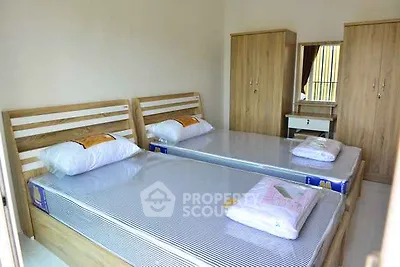 Spacious bedroom with twin beds and wooden furniture, perfect for comfortable living.