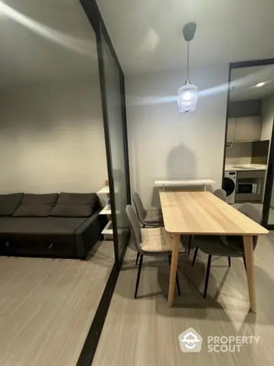 Modern apartment dining area with sleek furniture and open kitchen layout.