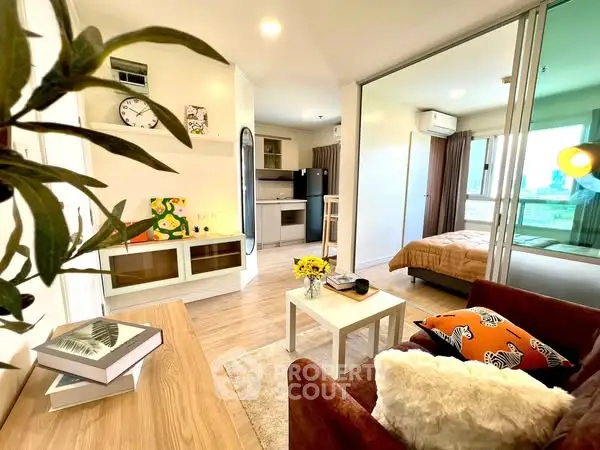 Modern open-plan living room with cozy decor and bedroom view in stylish apartment.