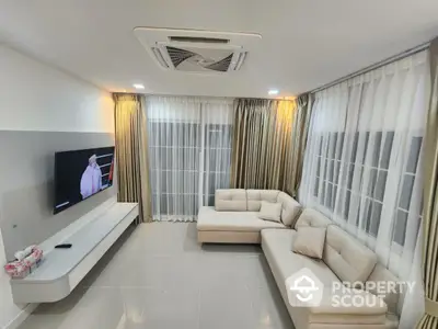 Modern living room with elegant sofa and large windows, perfect for relaxation and entertainment.