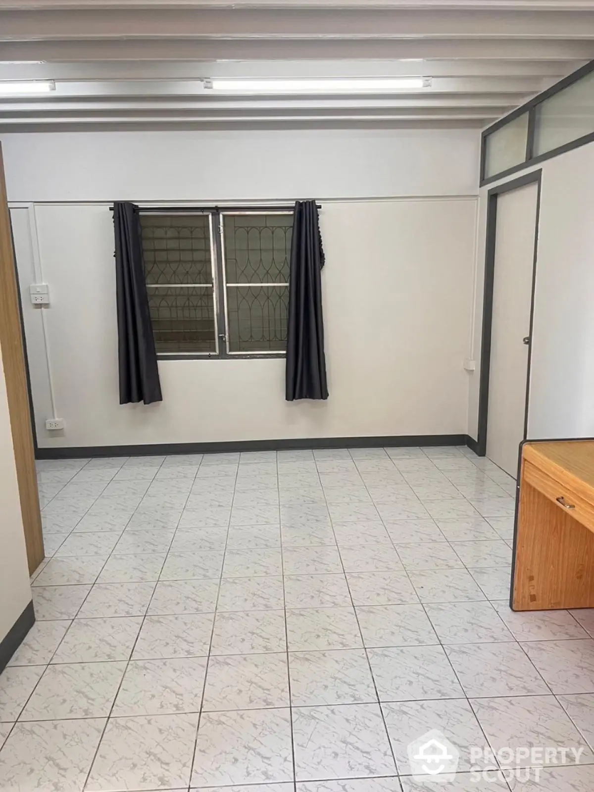 Spacious empty room with tiled floor and large window, ideal for customization.