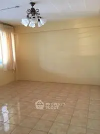 Spacious empty room with tiled floor and elegant chandelier