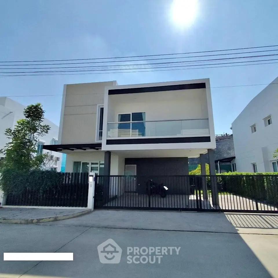 Modern two-story house with sleek design and spacious balcony under clear blue sky.