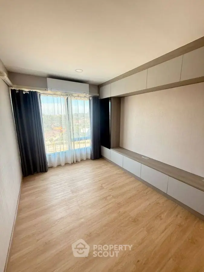 Spacious empty room with large window and wooden flooring