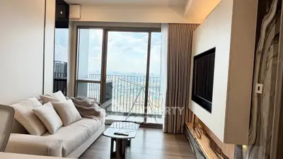 Modern living room with large windows and city view, featuring elegant decor and cozy seating.