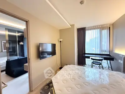 Modern bedroom with large window, stylish decor, and wall-mounted TV in a contemporary apartment.