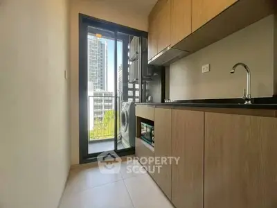 Modern kitchen with sleek cabinetry and city view from balcony.
