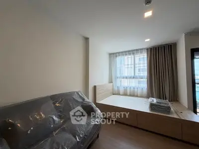 Modern bedroom with large window and cozy sofa, perfect for relaxation.