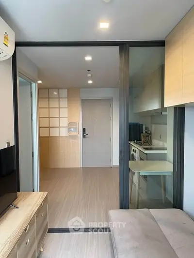 Modern apartment interior with sliding glass doors and compact kitchen area.
