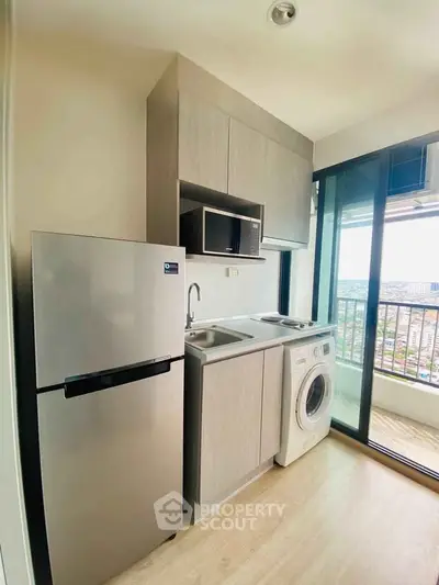 Modern compact kitchen with appliances and balcony view in urban apartment