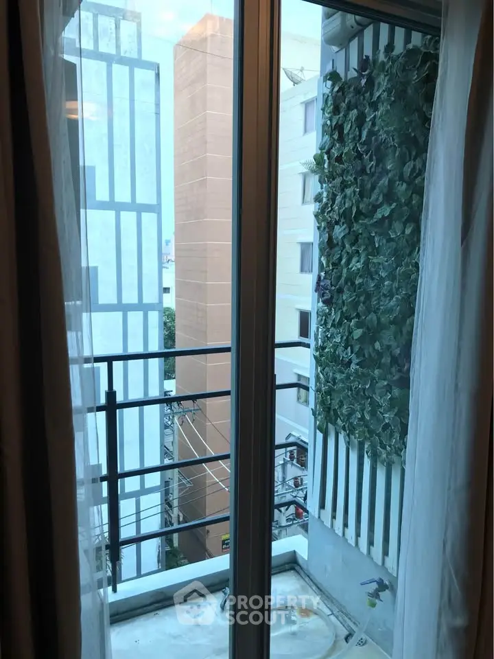 Charming urban balcony view with lush vertical garden and cityscape backdrop.