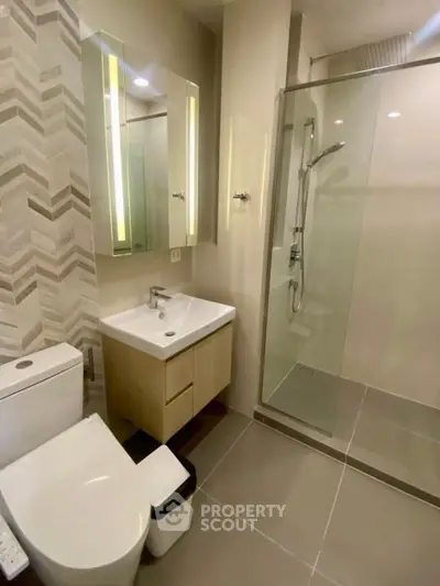 Modern bathroom with glass shower and sleek vanity in contemporary apartment.