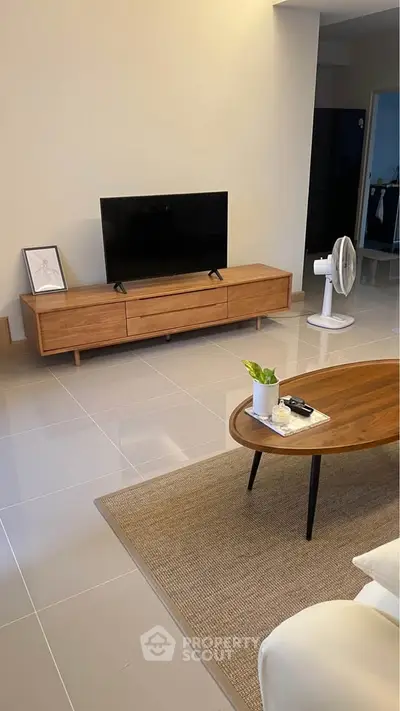 Modern living room with sleek TV stand and stylish coffee table on tiled floor.