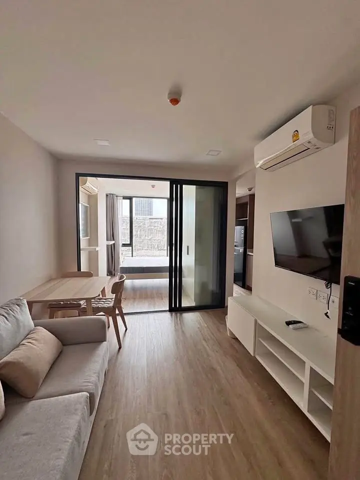 Modern living room with sleek design, featuring a cozy sofa, dining area, and large sliding glass doors.