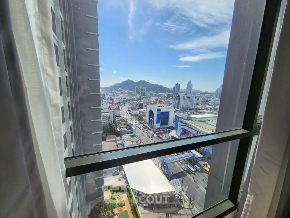 Stunning cityscape view from high-rise window with clear blue sky.